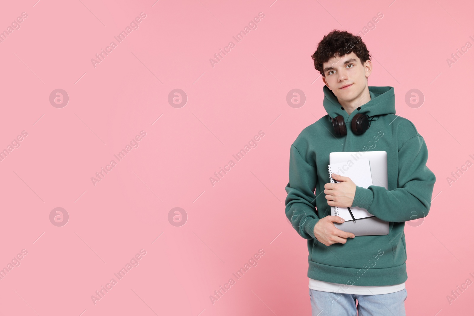 Photo of Portrait of student with laptop, notebook and headphones on pink background. Space for text