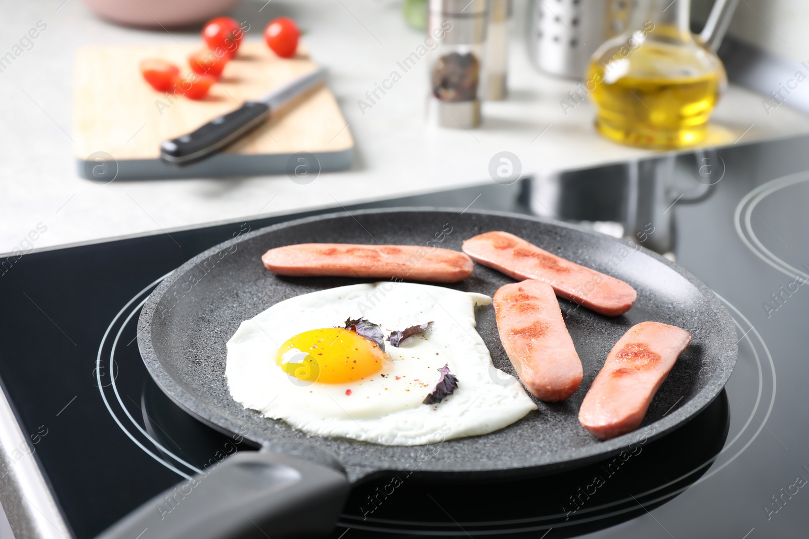 Photo of Egg and sausages in frying pan on stove indoors