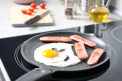 Photo of Egg and sausages in frying pan on stove indoors