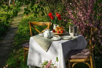 Beautiful bouquet of tulips and freshly baked waffles on table served for tea drinking in garden