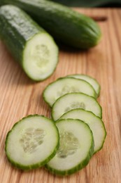 Photo of Cut ripe cucumber on wooden board, closeup