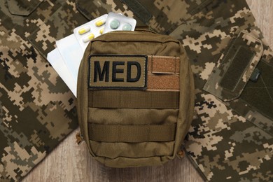 Photo of First aid kit and military uniform on wooden table, flat lay