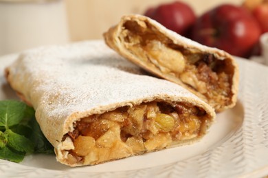 Photo of Delicious strudel with apples, nuts and raisins on plate, closeup