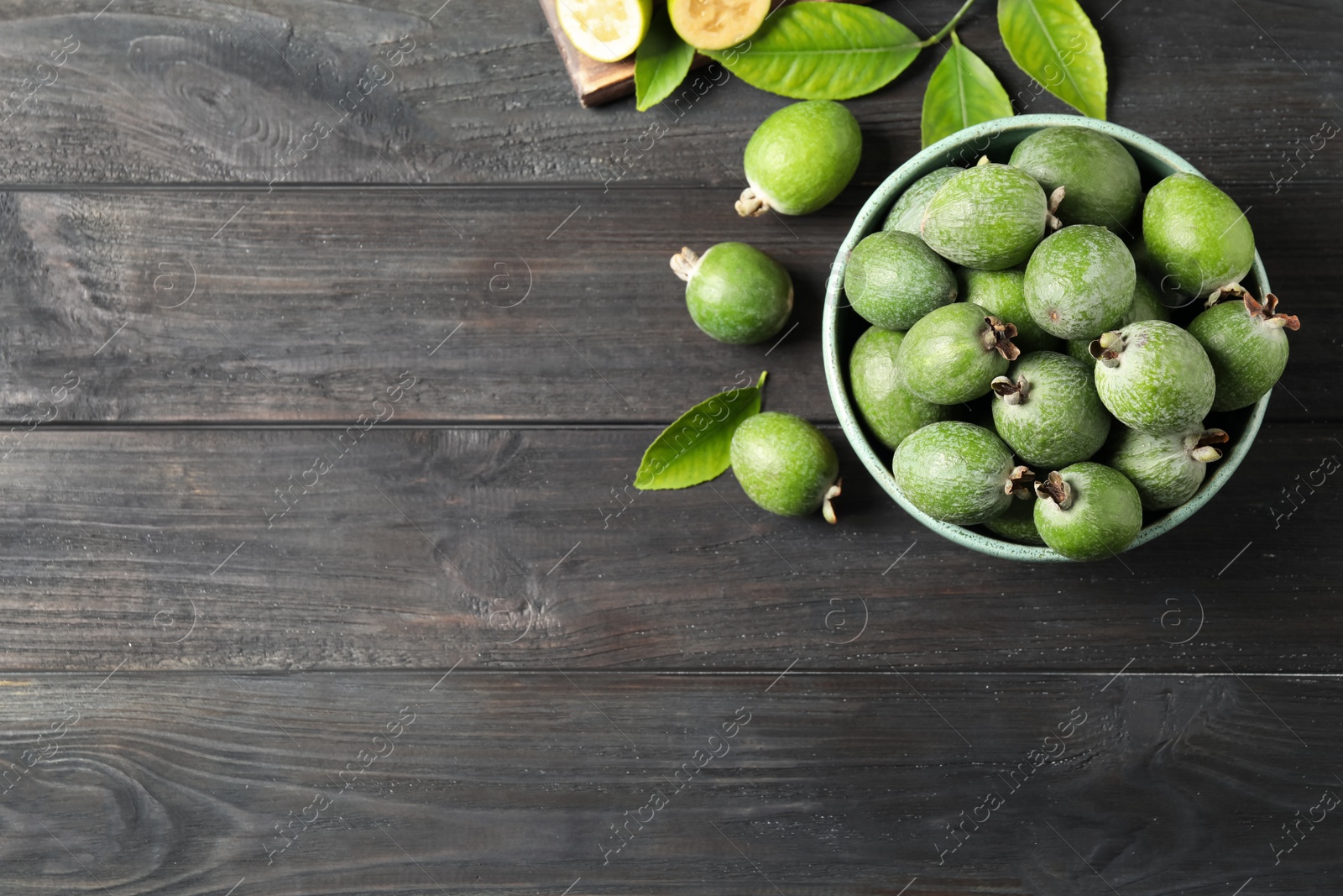 Photo of Flat lay composition with fresh green feijoa fruits on black wooden table, space for text