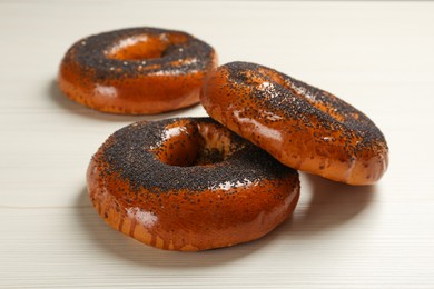 Delicious fresh bagels with poppy seeds on white wooden table