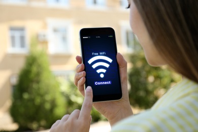 Image of Woman connecting to WiFi using mobile phone, closeup