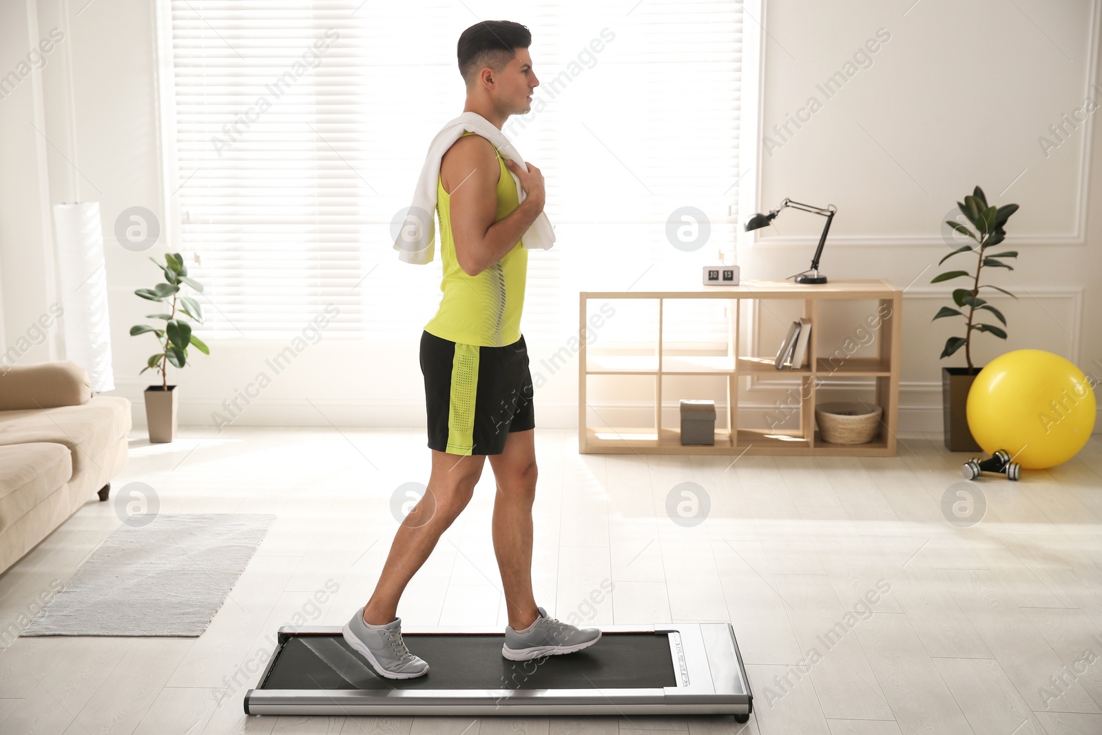 Photo of Sporty man training on walking treadmill at home