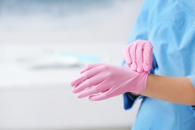 Photo of Doctor wearing medical gloves on color background. Space for text