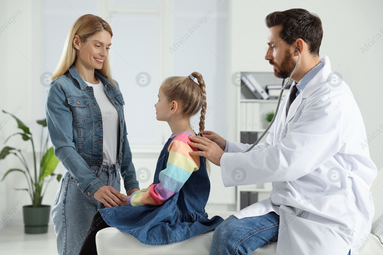 Photo of Happy mother and daughter having appointment with doctor. Pediatrician consulting patient in clinic