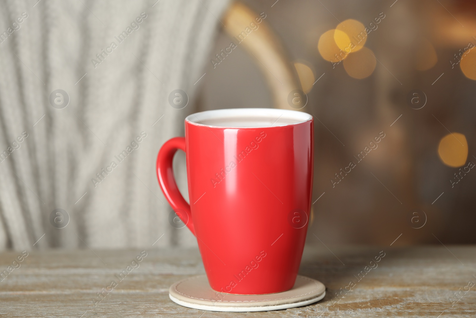 Photo of Cup of tasty cocoa on wooden table against blurred background