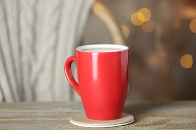 Cup of tasty cocoa on wooden table against blurred background