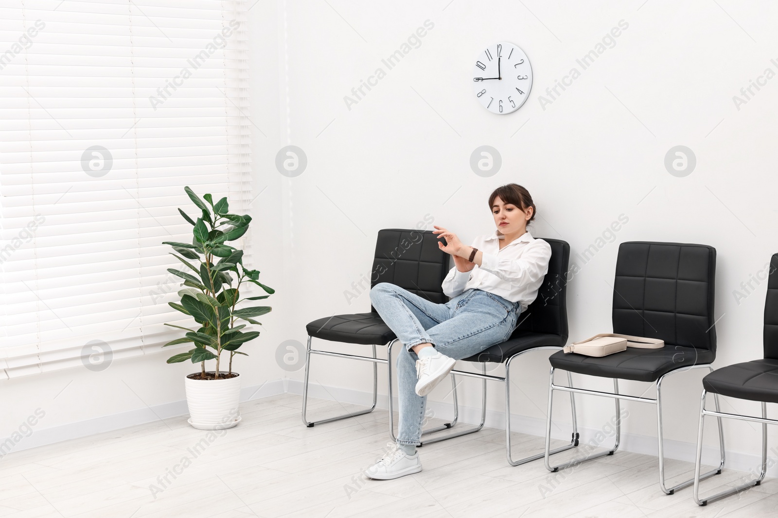 Photo of Woman looking at wrist watch and waiting for appointment indoors