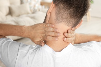 Photo of Closeup of man suffering from neck pain indoors, back view