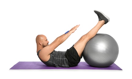 Overweight man doing exercise with fitness ball on white background