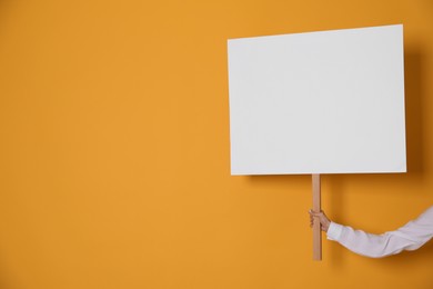 Woman holding blank sign on yellow background, closeup. Space for text