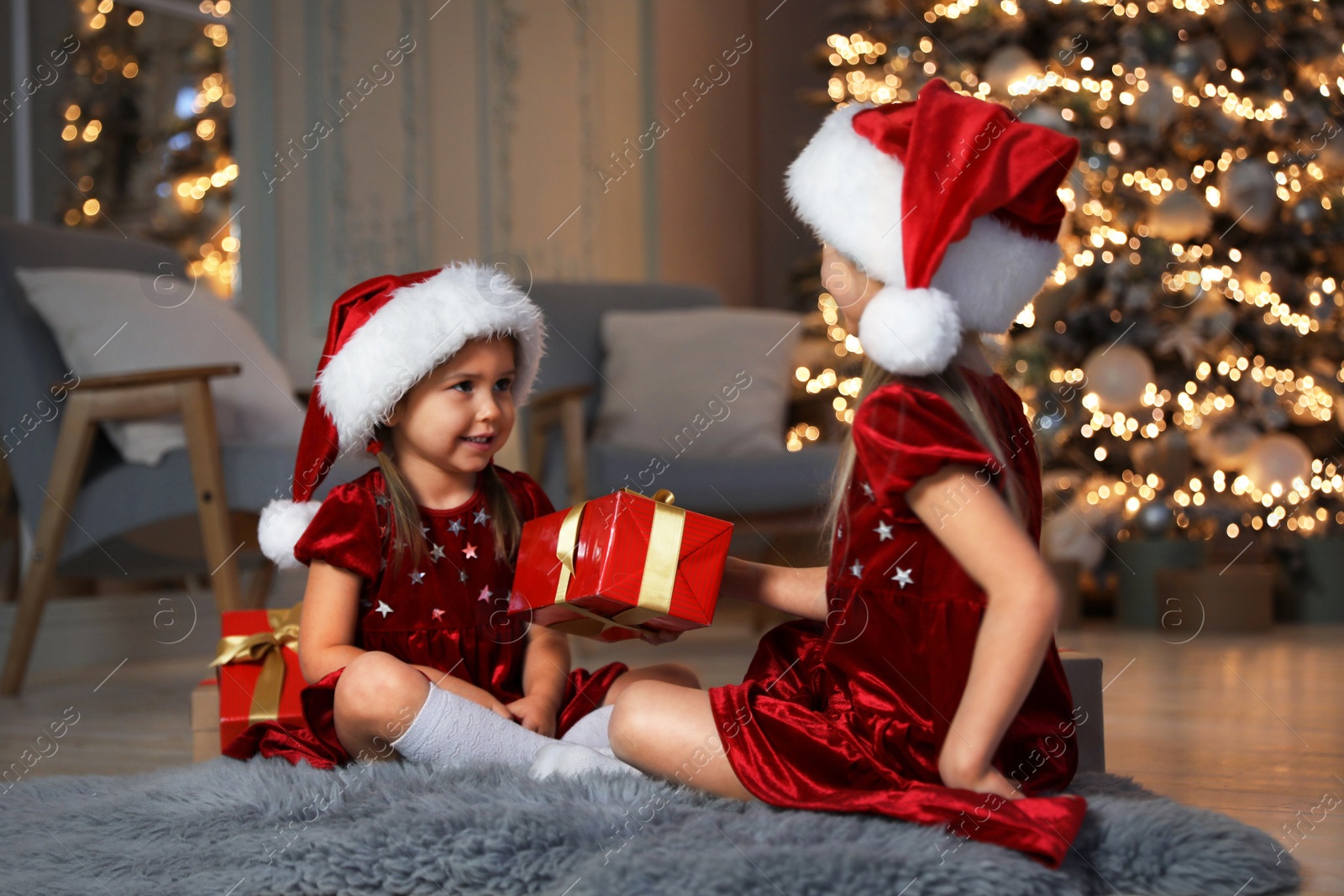 Photo of Cute little children with Christmas gift in living room