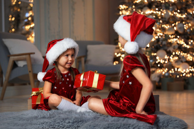 Photo of Cute little children with Christmas gift in living room