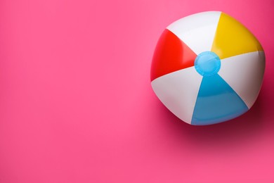 Photo of Bright beach ball on pink background, top view. Space for text