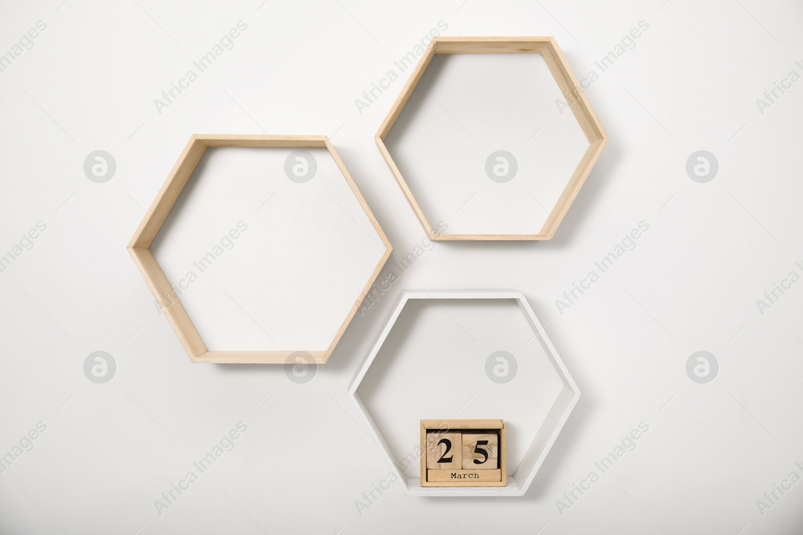 Photo of Honeycomb shaped shelves with wooden block calendar on white wall