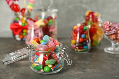 Photo of Jars with different delicious candies on grey table. Space for text