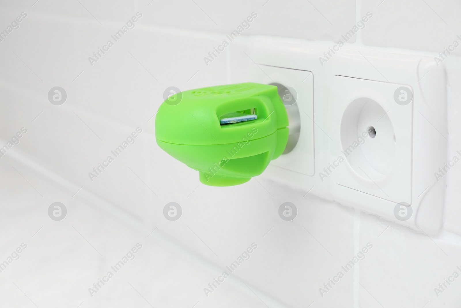 Photo of Electric mosquito device with insect repellent plate plugged in socket at home