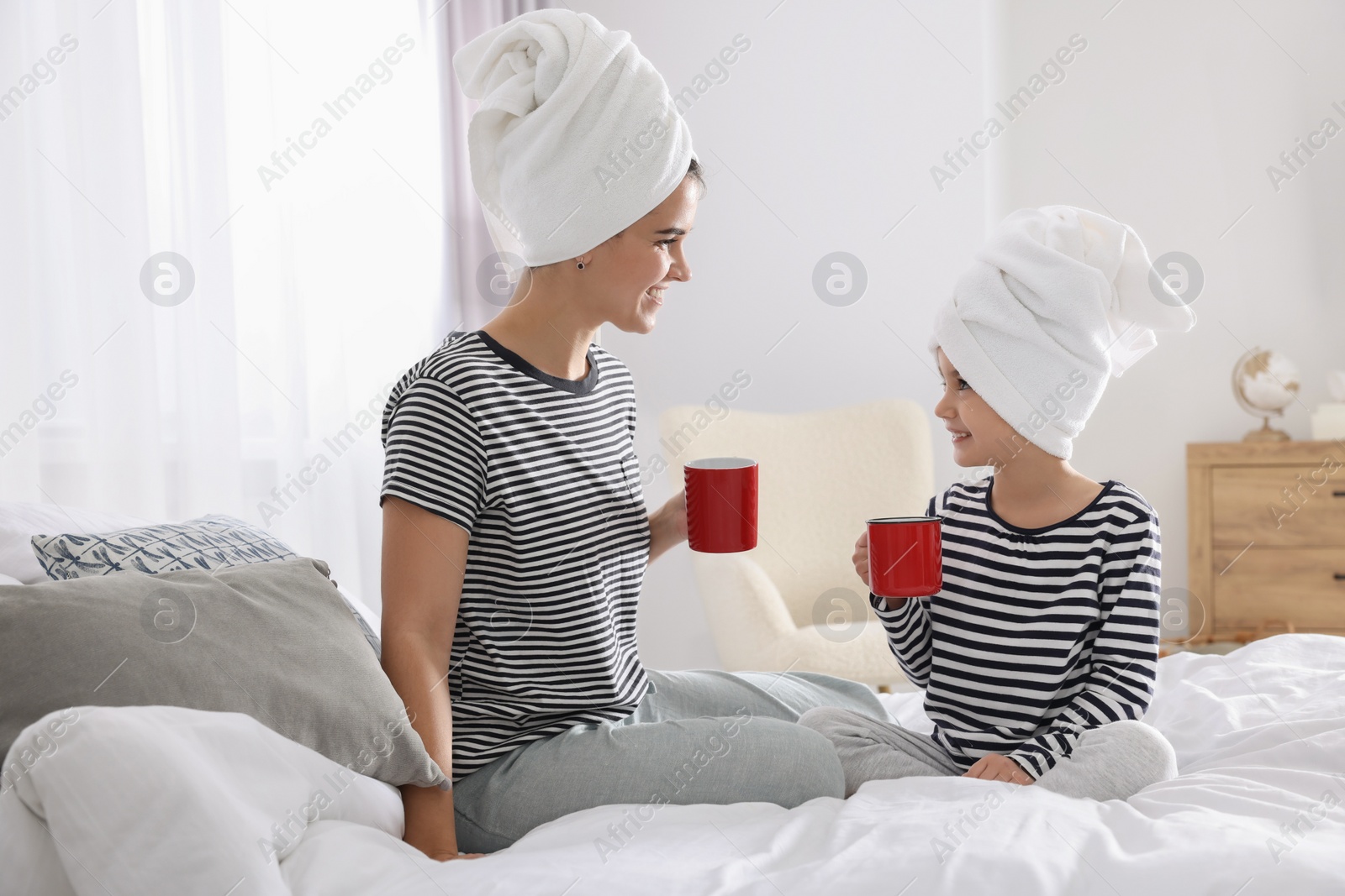 Photo of Young mother and her daughter spending time together on bed at home