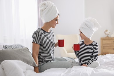 Photo of Young mother and her daughter spending time together on bed at home