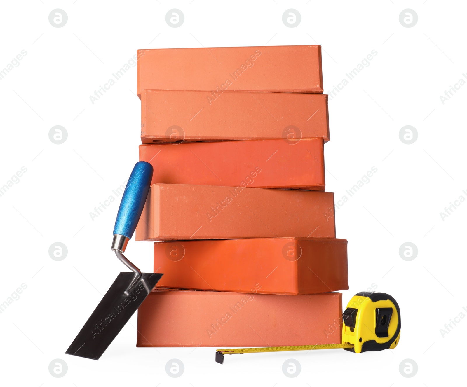 Photo of Many red bricks, trowel and tape measure on white background