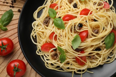 Photo of Delicious pasta with anchovies, tomatoes and basil on table, flat lay
