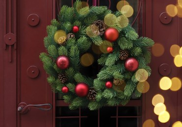 Photo of Beautiful Christmas wreath with red balls hanging on door