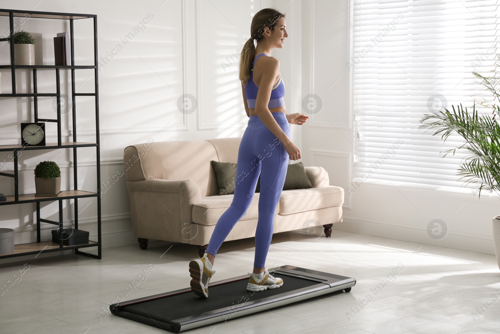Photo of Sporty woman training on walking treadmill at home