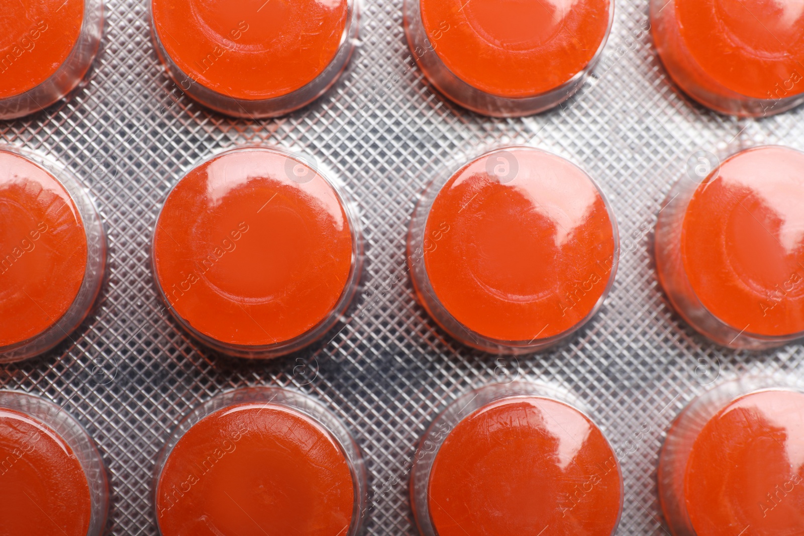 Photo of Blister with orange cough drops as background, closeup