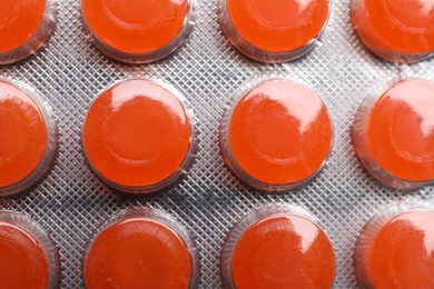 Photo of Blister with orange cough drops as background, closeup