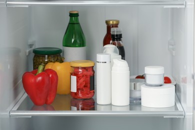 Photo of Different cosmetic products on shelf in refrigerator