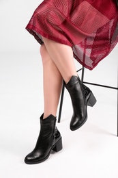 Photo of Woman in trendy shoes sitting on bar stool, light background