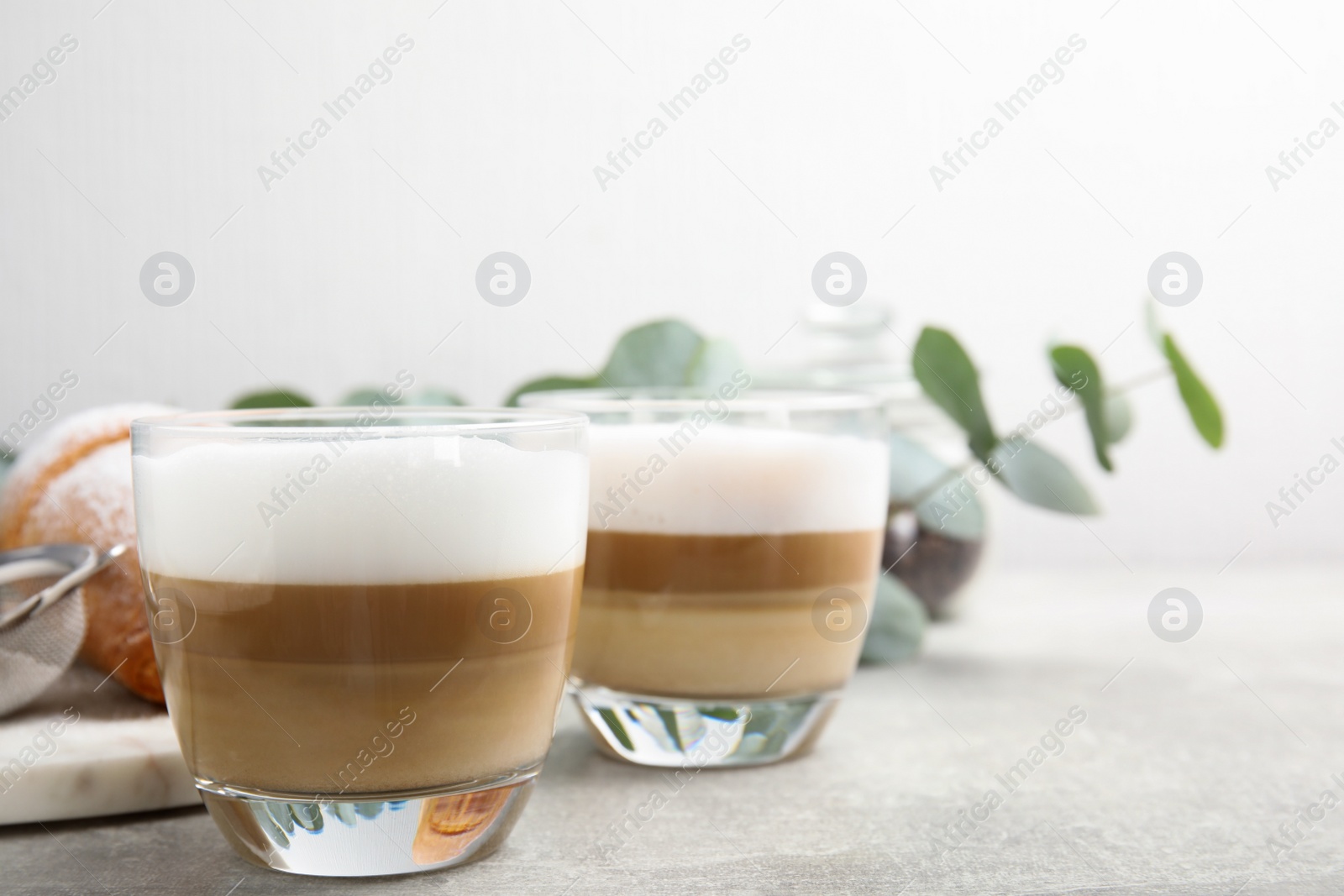 Photo of Delicious latte macchiato and croissant on grey table. Space for text