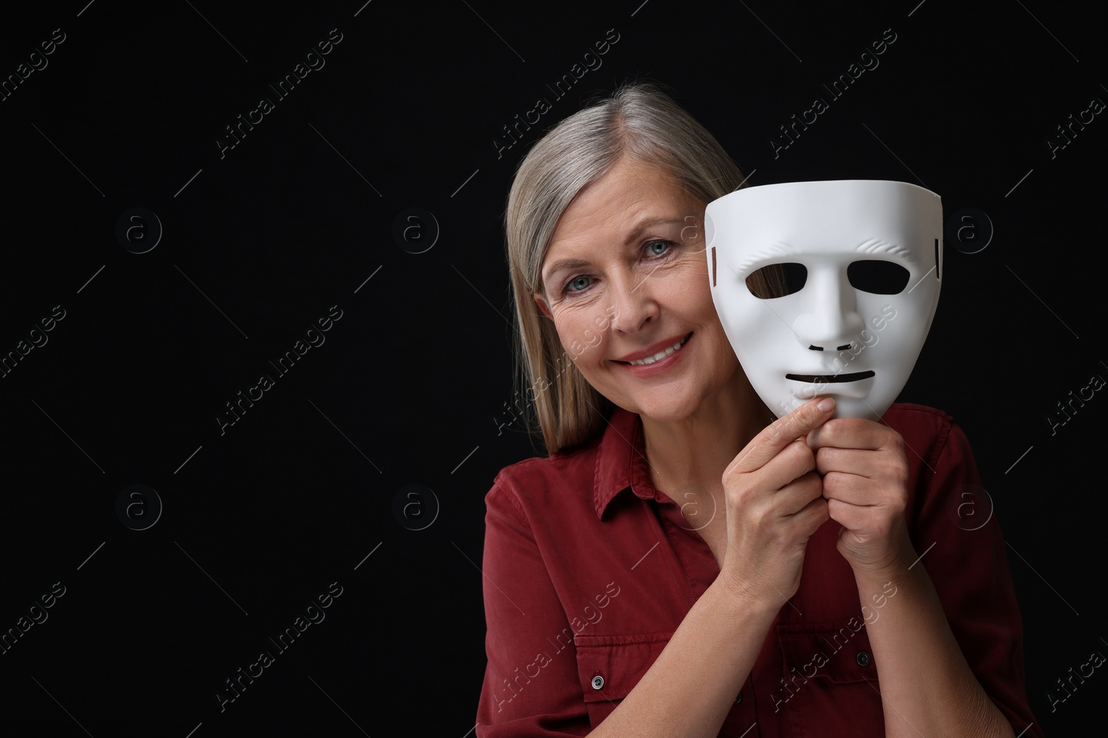 Photo of Multiple personality concept. Woman with mask on black background, space for text