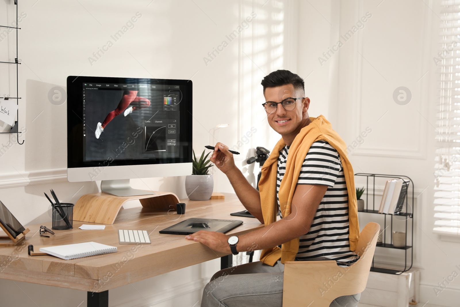 Photo of Professional retoucher working on graphic tablet at desk in office