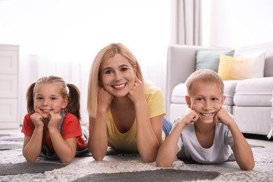 Photo of Happy mother with her children on floor at home