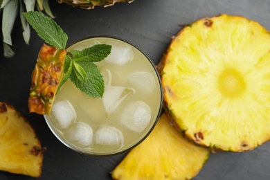 Delicious pineapple juice with fresh fruit and mint on black table, flat lay