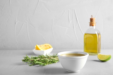 Photo of Bowl with fresh rosemary oil on table