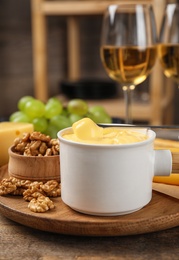 Pot of tasty cheese fondue and products on wooden table