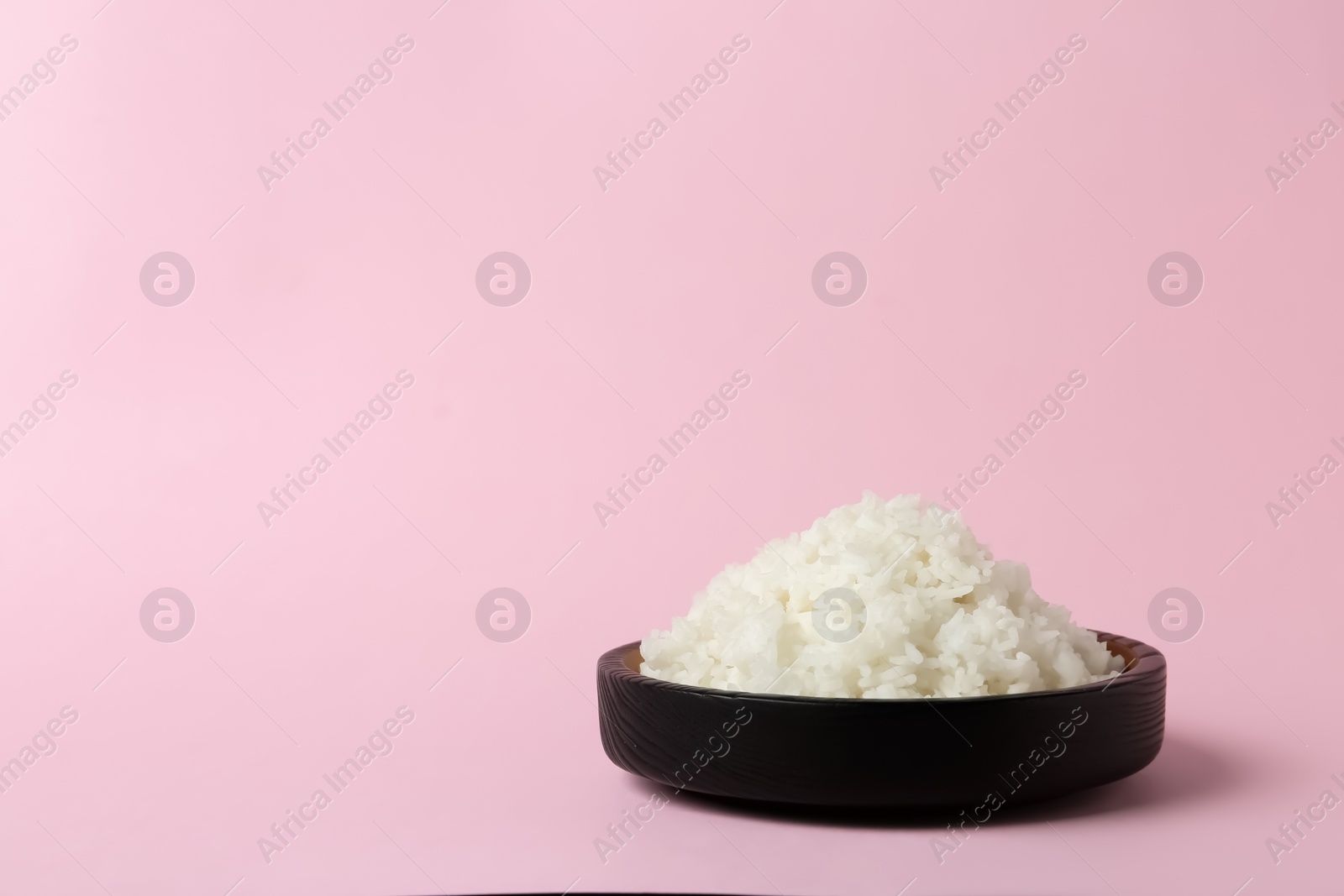 Photo of Bowl of boiled rice on color background. Space for text