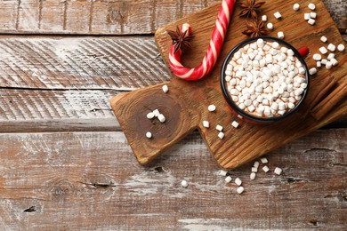 Photo of Tasty hot chocolate with marshmallows on wooden table, top view. Space for text