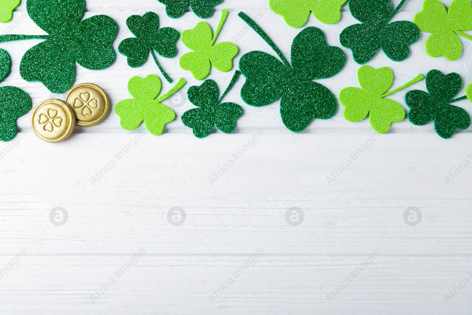 Photo of Flat lay composition with clover leaves on white wooden table, space for text. St. Patrick's Day celebration