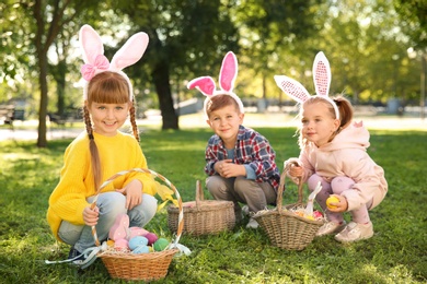 Cute little children hunting eggs in park. Easter tradition