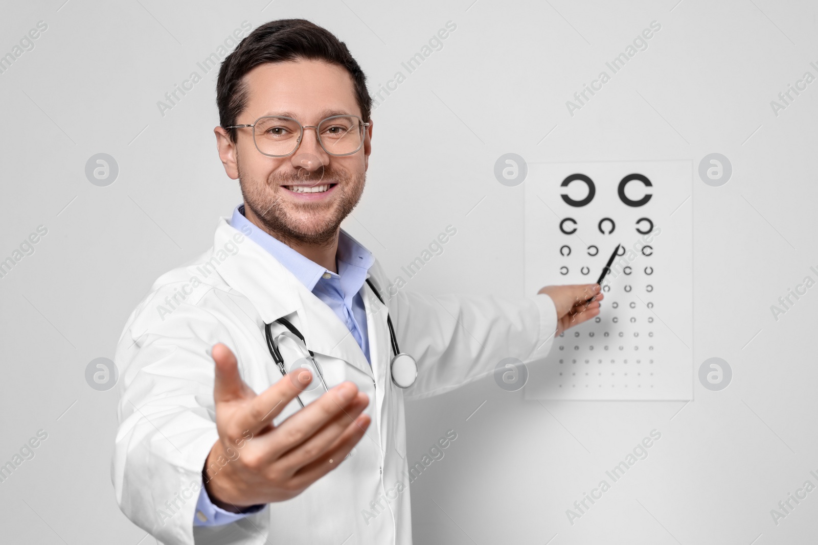 Photo of Ophthalmologist pointing at vision test chart on white wall