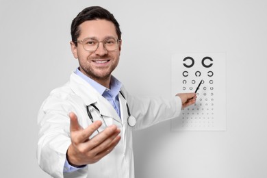 Ophthalmologist pointing at vision test chart on white wall