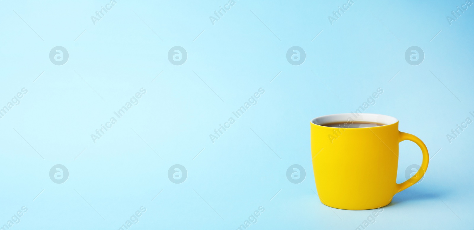 Photo of Yellow ceramic cup with hot aromatic coffee on color background