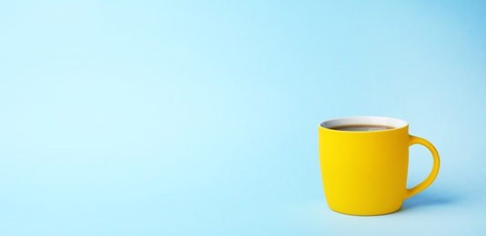Photo of Yellow ceramic cup with hot aromatic coffee on color background